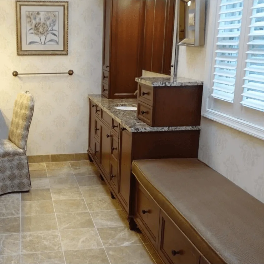 A long bathroom hallway featuring dark wood cabinetry, a built-in seating bench, and tiled floors.